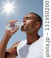 Thirsty athletic man drinking water to cool down on a hot sunny day. 131950200