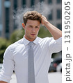 Exhausted businessman wiping sweat off his brow on a hot sunny day in the city. 131950205