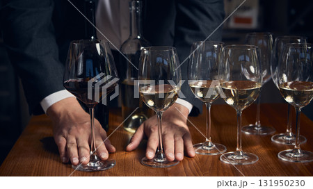 Sommelier comparing red and white wines during elegant tasting session 131950230