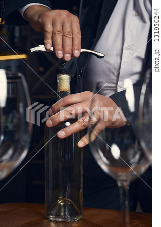 Sommelier opening white wine bottle with steady hands and focus 131950244