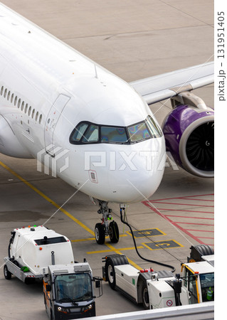 Modern regional  jet aircraft airport tarmac connected to ground vehicles for refueling maintenance. Engine cockpit clearly visible crew performs technical operations before next scheduled flight 131951405