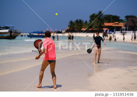 People playing beach tennis on a sunny day on a tropical beach with clear water and palm trees in the background. Redang Island. Malaysia 131951436
