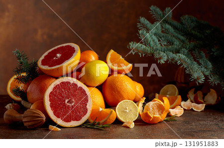 Citrus fruits and branch of spruce on a brown background. Citrus fruits and branch of spruce on a brown background. 131951883