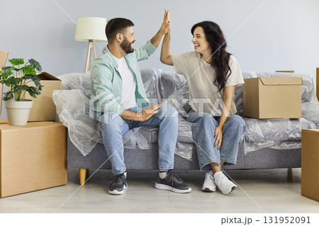 Happy couple celebrating first moving day with with high five and laughter 131952091