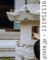 A child's hand stacking stones on a stone statue to make a wish. 131952116