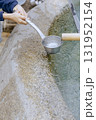 Close-up of a child's hand receiving clean, cool, flowing medicinal water from a ladle. 131952154