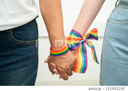 Asian LGBT couple woman holding hand wearing rainbow wristband. 131952192