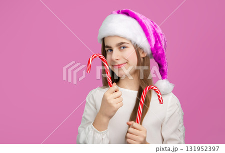 Girl with Christmas Hat Holding Tree-Shaped Candy. Festive girl in purple Santa hat holding Christmas tree Girl with Christmas Hat Holding Tree-Shaped Candy. Festive girl in purple Santa hat holding Christmas tree 131952397