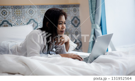 Asian Woman Working on Laptop in Bed Focused on Online Work from Home Asian Woman Working on Laptop in Bed Focused on Online Work from Home 131952564
