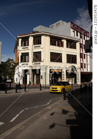 Yellow car passing colonial building on a sunny street corner 131953476