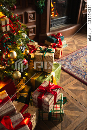 Many gift boxes in classical Christmas decorated interior living room library with fireplace. Christmas gift near fir tree. Modern classic style interior design apartment. Christmas eve at home 131954334