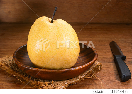 Single juicy ripe chinese pear or Pyrus pyrifolia in wooden dish. Single juicy ripe chinese pear or Pyrus pyrifolia in wooden dish. 131954452