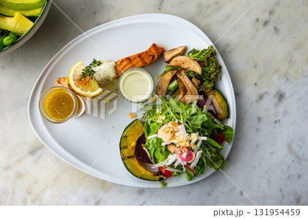 Top view of roasted salmon steak cooked with various vegetable salad. 131954459