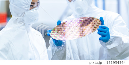 半導体工場でシリコンウエハーを検査する防塵服を着た男性作業員 131954564