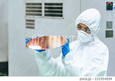 半導体工場でシリコンウエハーを検査する防護服を着た女性作業員 131954694
