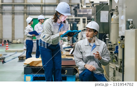 タブレットを持って工場機械を点検する男女作業員 タブレットを持って工場機械を点検する男女作業員 131954702