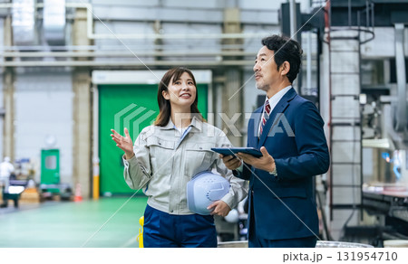 工場を視察する男性ビジネスパーソンと女性作業員 131954710