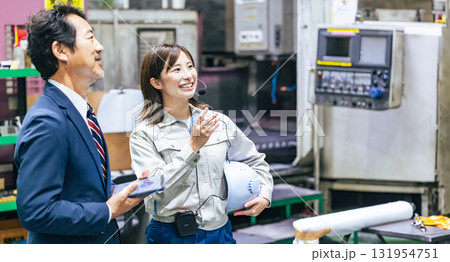 工場を視察する男性ビジネスパーソンと女性作業員 工場を視察する男性ビジネスパーソンと女性作業員 131954751