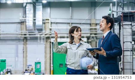 工場を視察する男性ビジネスパーソンと女性作業員 工場を視察する男性ビジネスパーソンと女性作業員 131954753