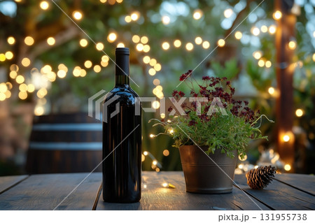 Elegant wine bottle placed on a rustic wooden table, adorned with a potted plant and pinecone, creating a cozy ambiance under warm string lights in a garden setting 131955738