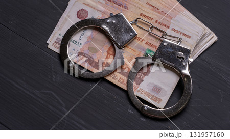 A pair of handcuffs is on top of a stack of Russian banknotes A pair of handcuffs is on top of a stack of Russian banknotes 131957160