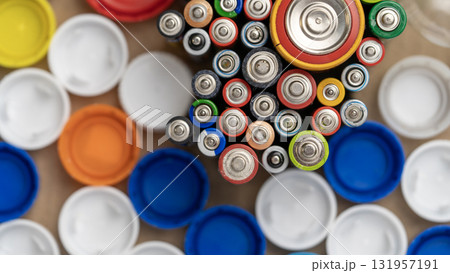 A bunch of batteries are on a table with a bunch of plastic caps A bunch of batteries are on a table with a bunch of plastic caps 131957191