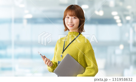 パソコンとスマートフォンを持つ笑顔の女性・ビジネスウーマン 131958632