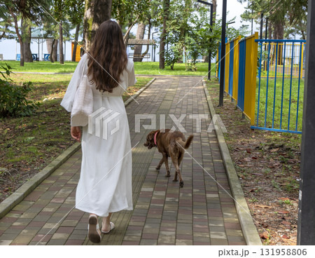 Attractive woman wearing creamy, off white outfit, straw hat in the park for a walk 131958806