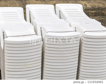 Set of white plastic patio chaise lounge at the beach Set of white plastic patio chaise lounge at the beach 131958981
