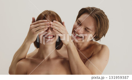 Laughing couple in intimate playful pose with eyes covered in trust 131959387