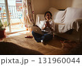 Woman Working From Home With Laptop and Phone in Cozy Living Room by Balcony 131960044