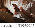 Cozy Home Office Scene With Person Using Smartphone And Laptop On Lap 131960047