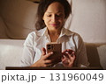 Woman Relaxing On Couch Using Smartphone At Home With Warm Lighting And Comfortable Vibe 131960049