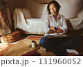 Relaxed Woman Working From Home With Laptop, Coffee Mug, and Cozy Living Room Setting 131960052