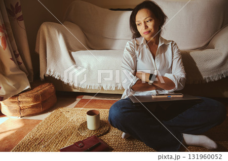 Relaxed Woman Working From Home With Laptop, Coffee Mug, and Cozy Living Room Setting Relaxed Woman Working From Home With Laptop, Coffee Mug, and Cozy Living Room Setting 131960052