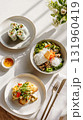 Vietnamese cuisine with fresh spring rolls, noodle salad, fish dish, and dipping sauce in sunlit setting. 131960419