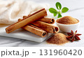 Aromatic cinnamon sticks and ground spice with anise and fresh greenery on marble surface. 131960420