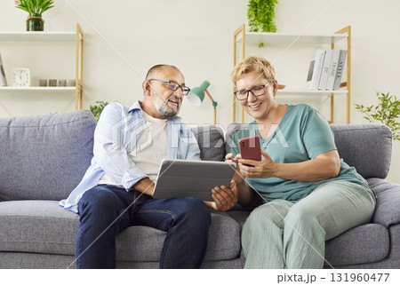 Senior couple using tablet and smartphone on sofa, learning digital skills Senior couple using tablet and smartphone on sofa, learning digital skills 131960477