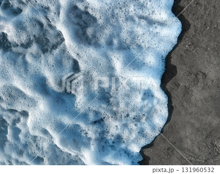 Sea foam creating texture on dark beach sand Sea foam creating texture on dark beach sand 131960532