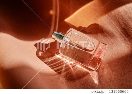 A pink perfume bottle on a soft reddish background. 131960663