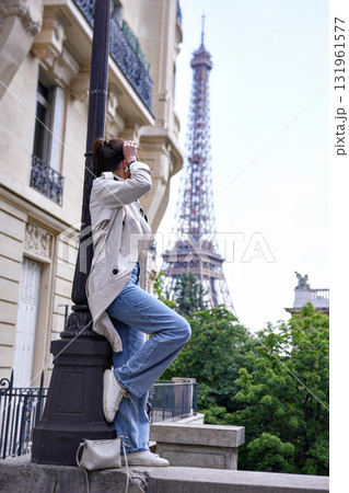 Playful woman climbing lamppost on Paris street with Eiffel Tower view Playful woman climbing lamppost on Paris street with Eiffel Tower view 131961577