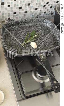 Rosemary and sage sprigs, garlic in frying pan. Spices and cooking at home in kitchen. 131961834