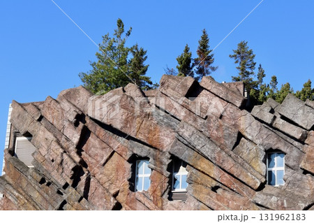 Building facade designed with rock like textured panels blending with natural trees and the blue sky. Antwerp, Belgium 131962183