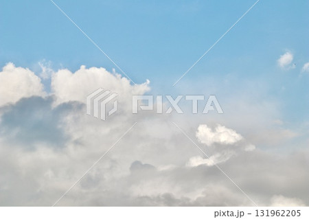 A mix of dark grey storm clouds and bright white cumulus formations against a pale blue sky, showing the transition of weather and dramatic atmospheric contrast. A mix of dark grey storm clouds and bright white cumulus formations against a pale blue sky, showing the transition of weather and dramatic atmospheric contrast. 131962205