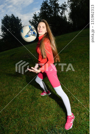 Young woman in vibrant sportswear playing with soccer ball outdoors Young woman in vibrant sportswear playing with soccer ball outdoors 131962313