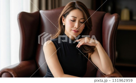 椅子に座り物思いにふける黒いワンピースの40代女性 131962959