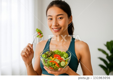 Smiling Woman Holding a Fresh Salad Bowl While Enjoying a Healthy Meal at Home Smiling Woman Holding a Fresh Salad Bowl While Enjoying a Healthy Meal at Home 131963056