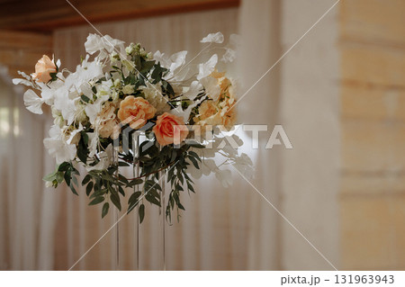 White floral wedding arrangement on metal stand with blurred lights in background 131963943