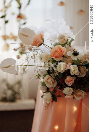 White floral wedding arrangement on metal stand with blurred lights in background 131963946