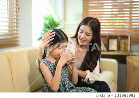Asian mother caring for her daughter drinking milk at home Asian mother caring for her daughter drinking milk at home 131963992
